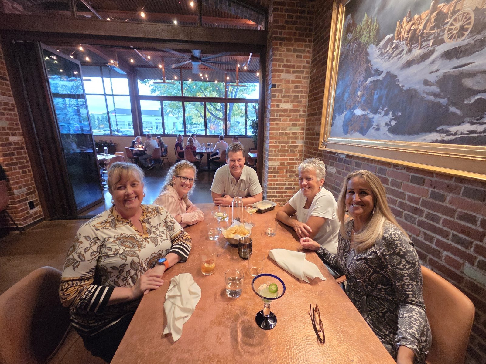 Five members of the SWP team seated around a copper-topped restaurant table with drinks