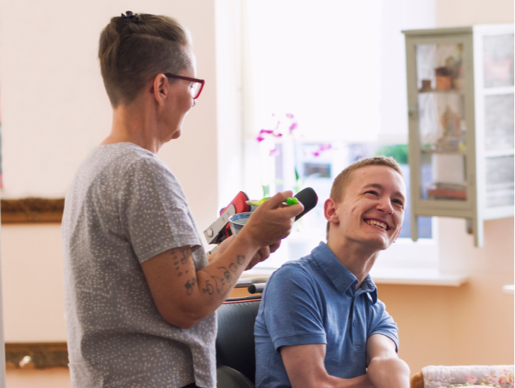 Person in wheelchair smiling talking to person standing