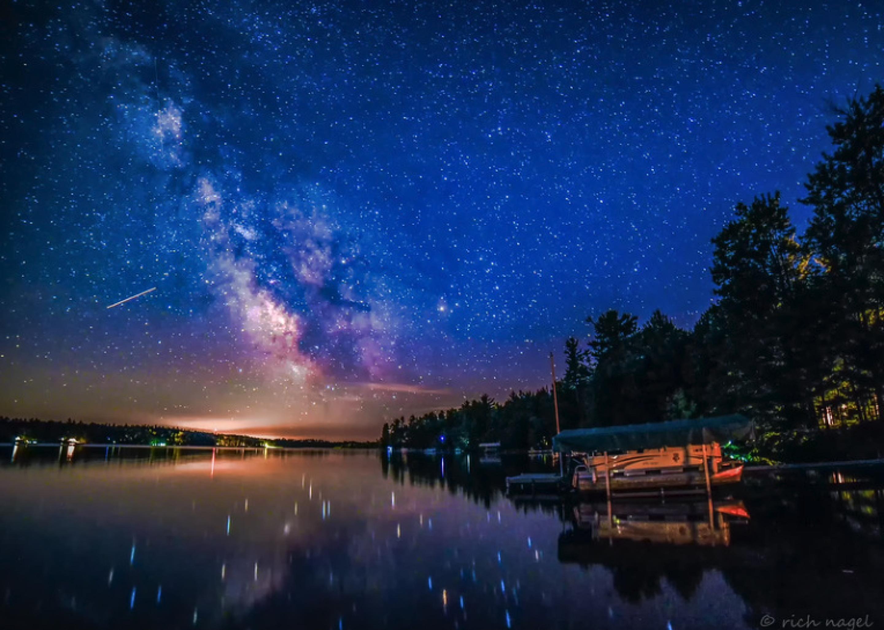 Vibrant, starry night sky with a body of water below it