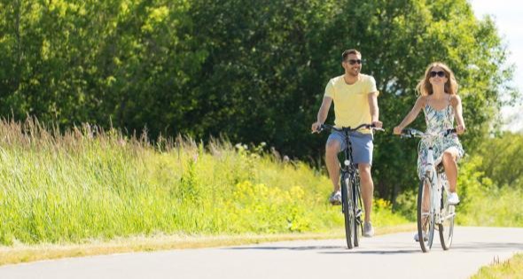 two people riding bicycles on a path on a sunny summer day