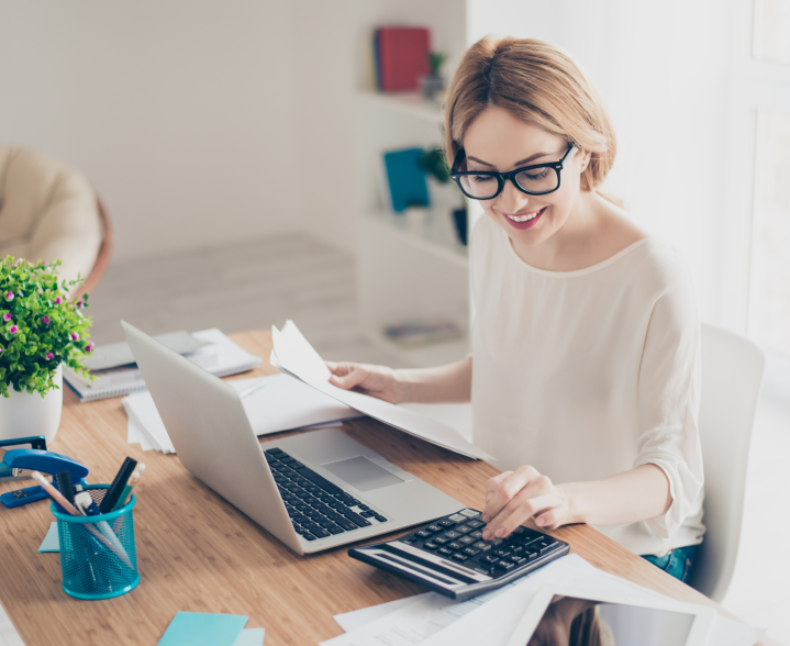 Photo of woman smiling while using calculator