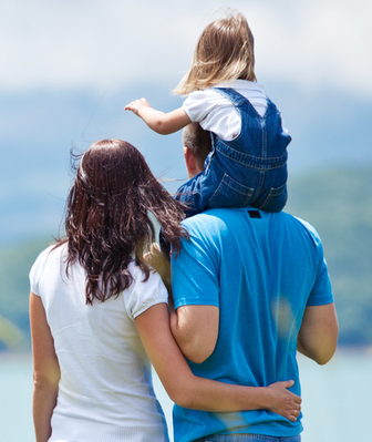 Dad carrying his kid on his shoulders with the mother at his side