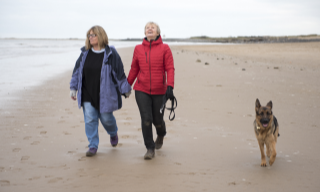 Couple-walking-dog-on-beach