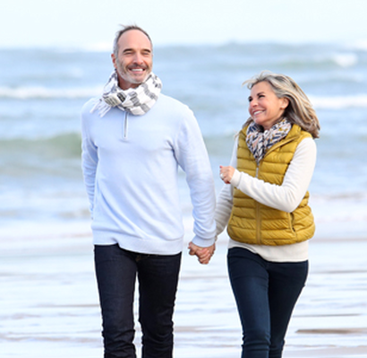 A happy couple holding hands with a body of water in the background