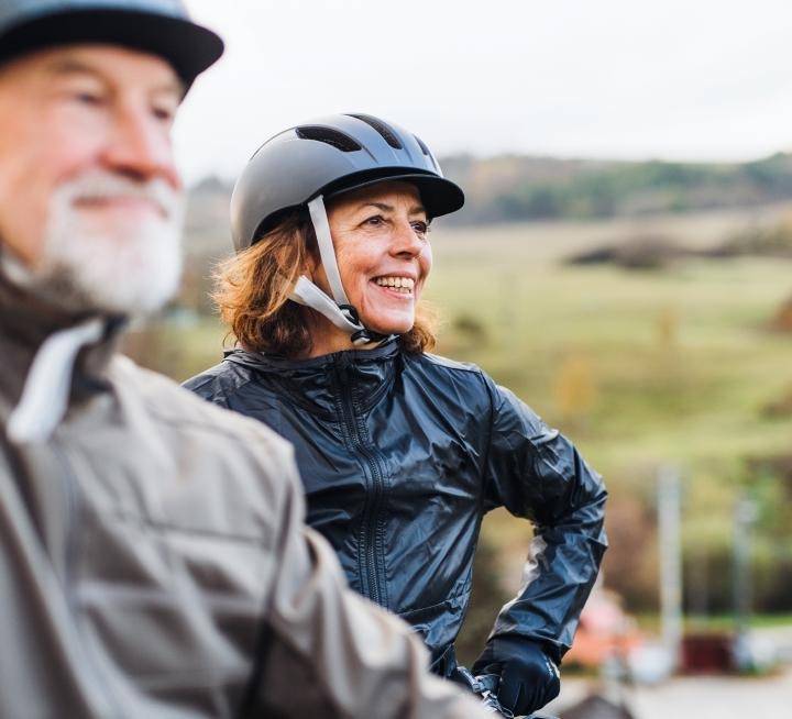 Two cyclists out on an overcast day, smiling.