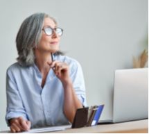 woman sitting in front of a laptop and looking off into the distance