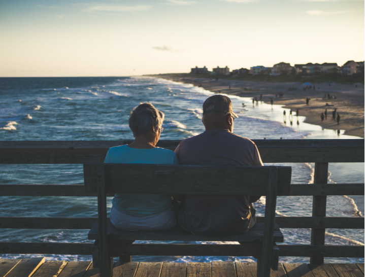 couple sitting on a bench next to the ocean