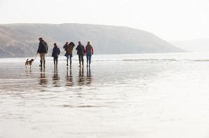 group of people walking next to a lake with their dog