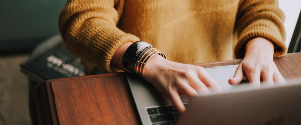 Hands typing on a laptop