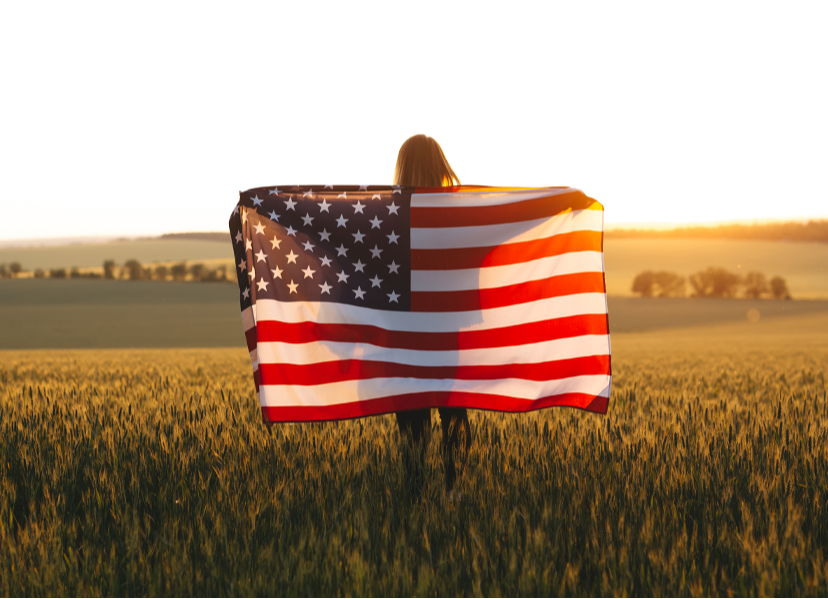 A girl holding an American Flag  on her back facing backwards
