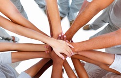 People in a circle putting their hands in the center