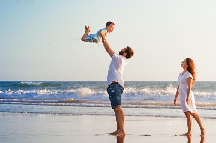 Couple playing with their young child on a beach