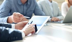 Business professionals collaborating on a tablet.