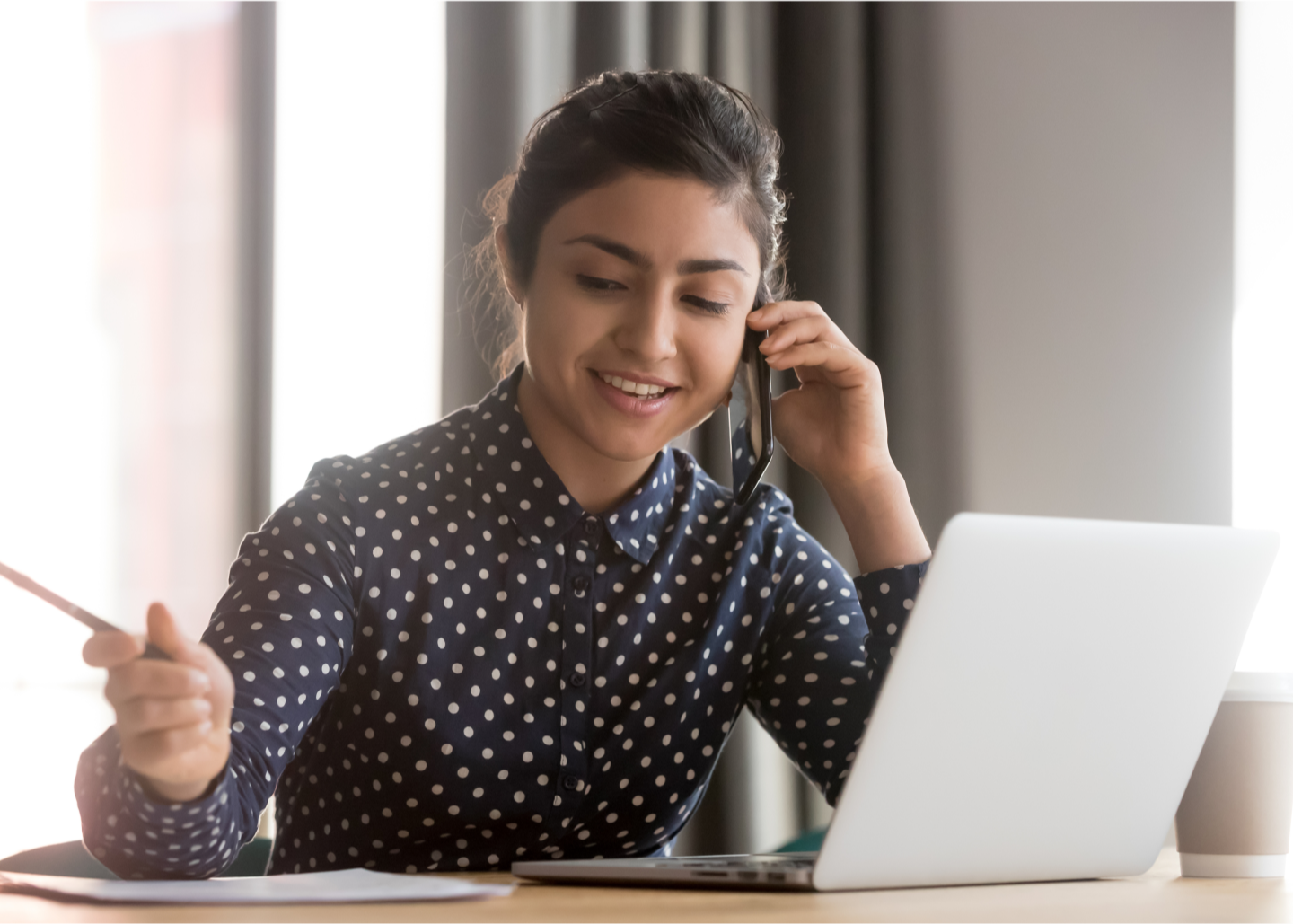 Indoors, office - Woman at desk working while on a phone call