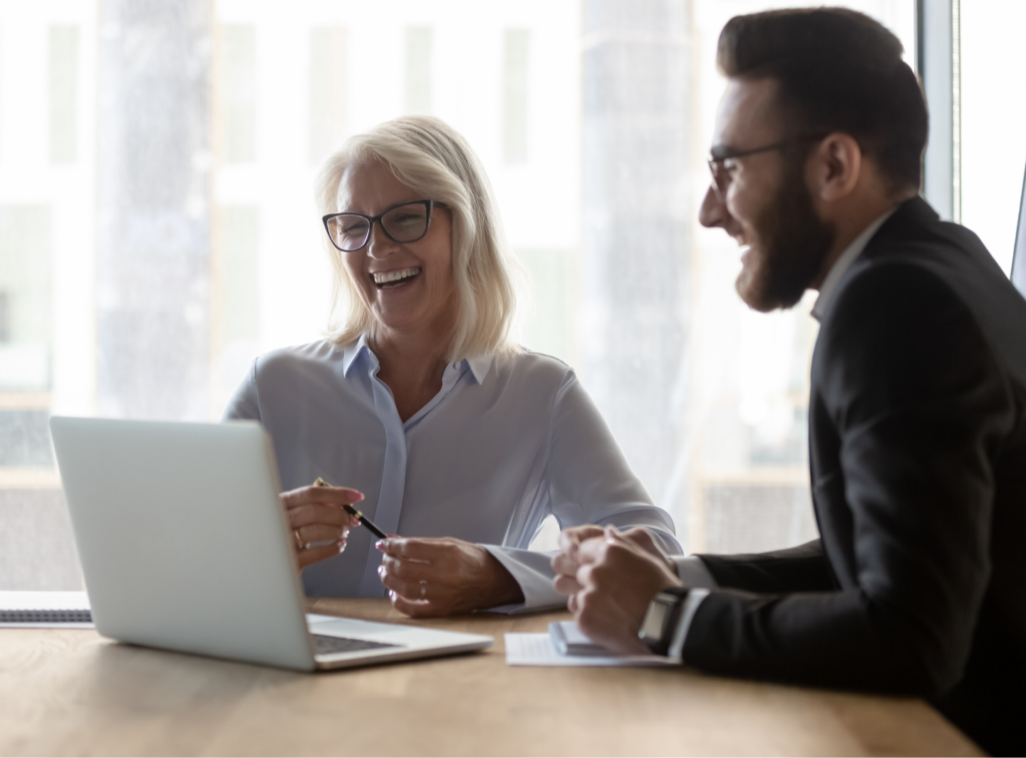 Two professionals laughing at a laptop