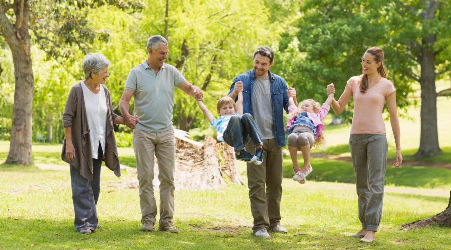 multi-generational family swinging the children between them on a summer walk