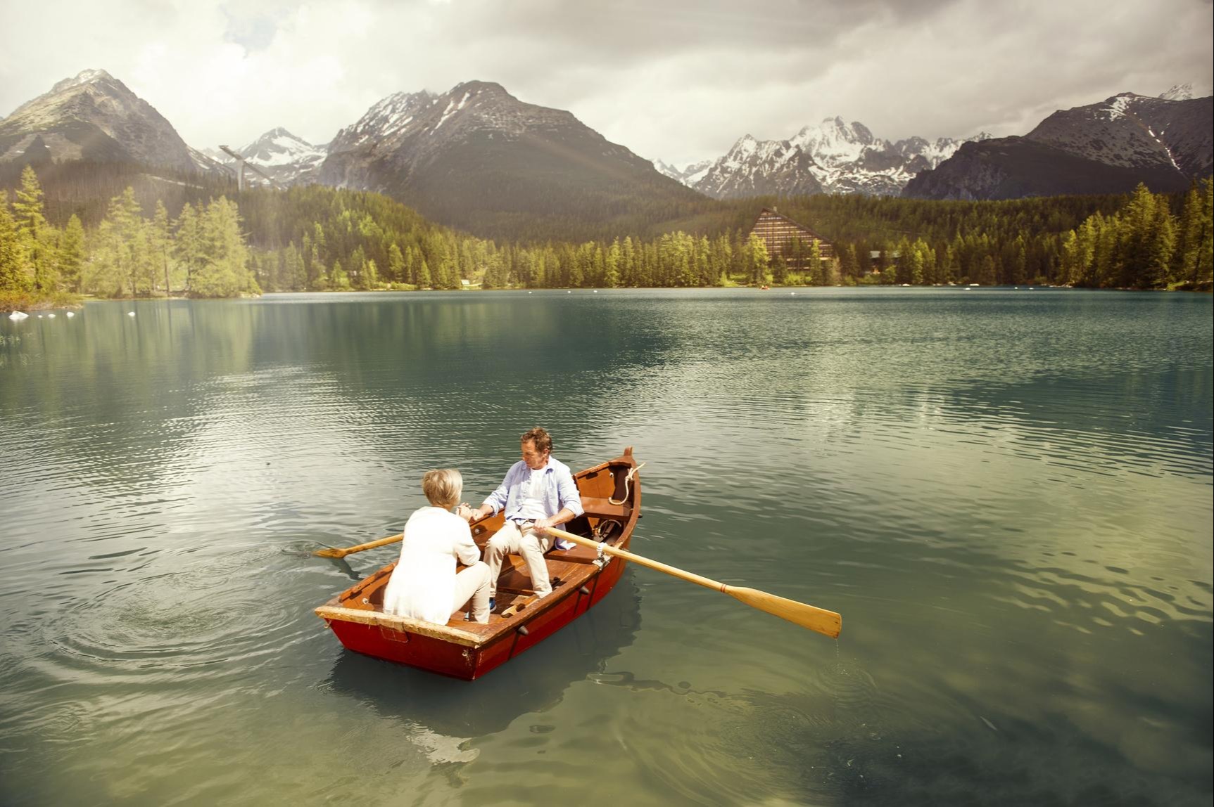 couple rowing a boat on a mountain lake