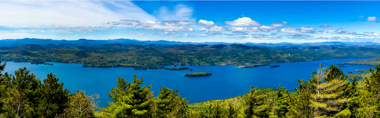View looking down at a blue lake with mountains in the distance