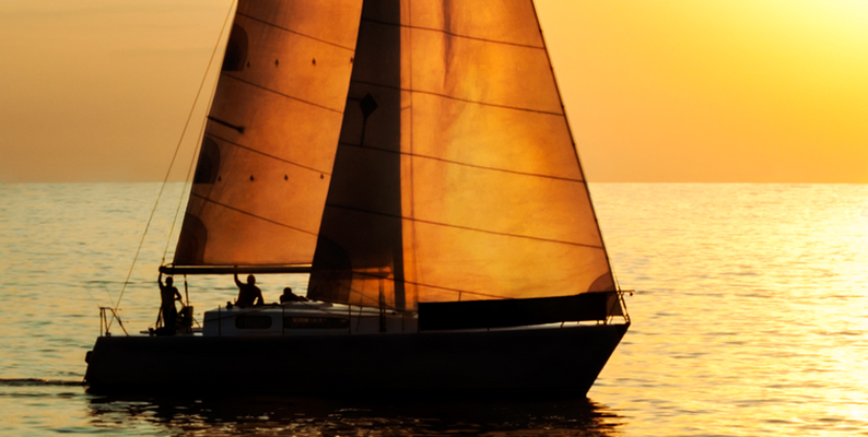 people sailing a sailboat at sunset