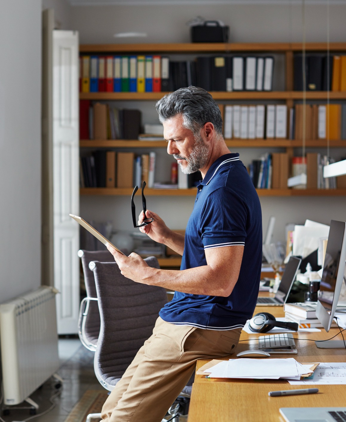 Man leaning against a desk and reading a document