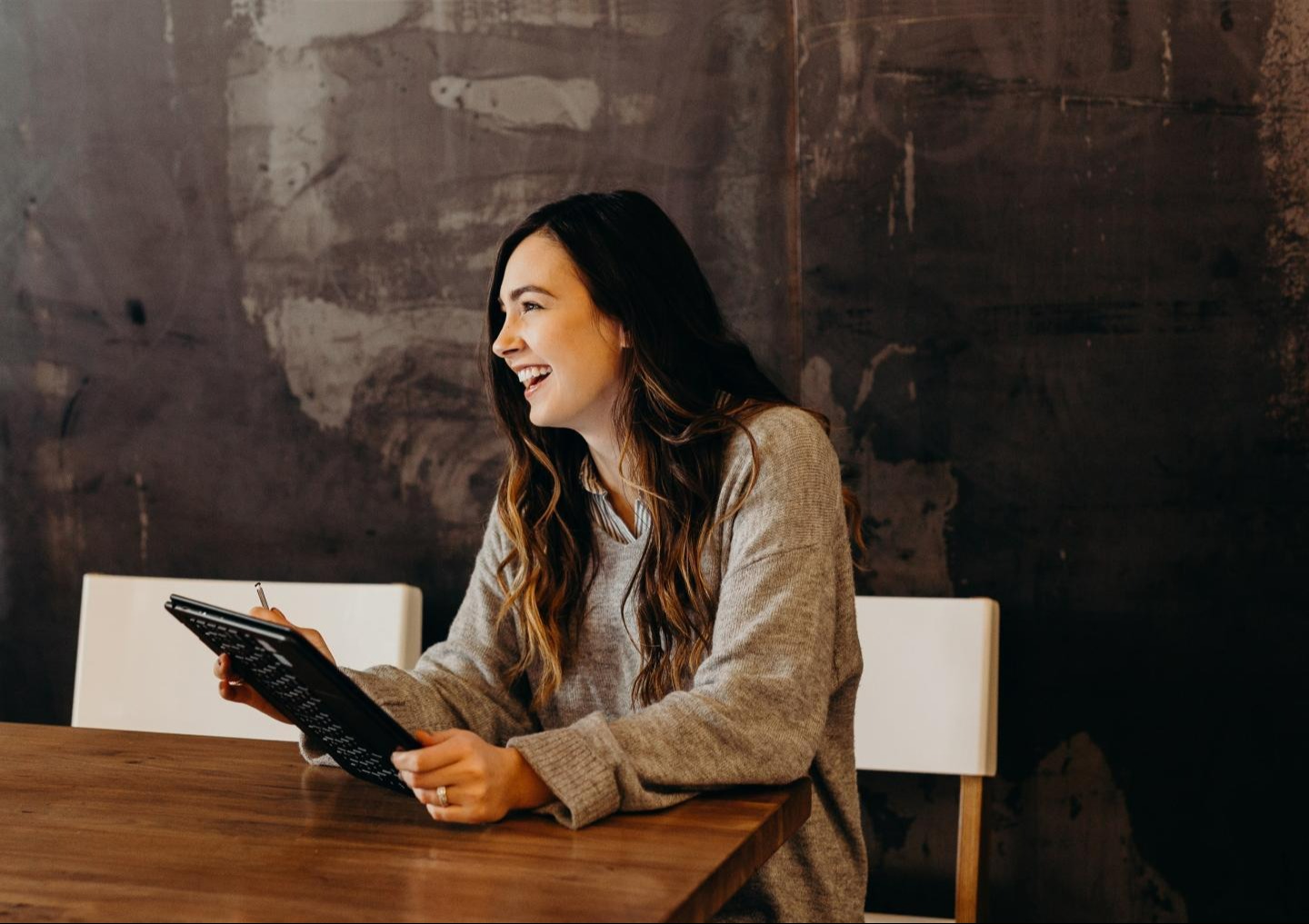 Woman holding tablet at a desk and smiling