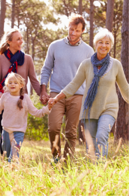 Family holding hands and walking through a forest