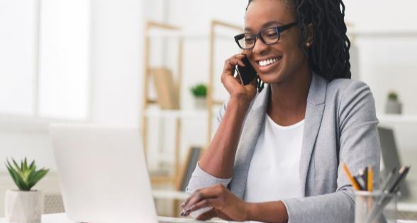 woman talking on cellphone and working on laptop