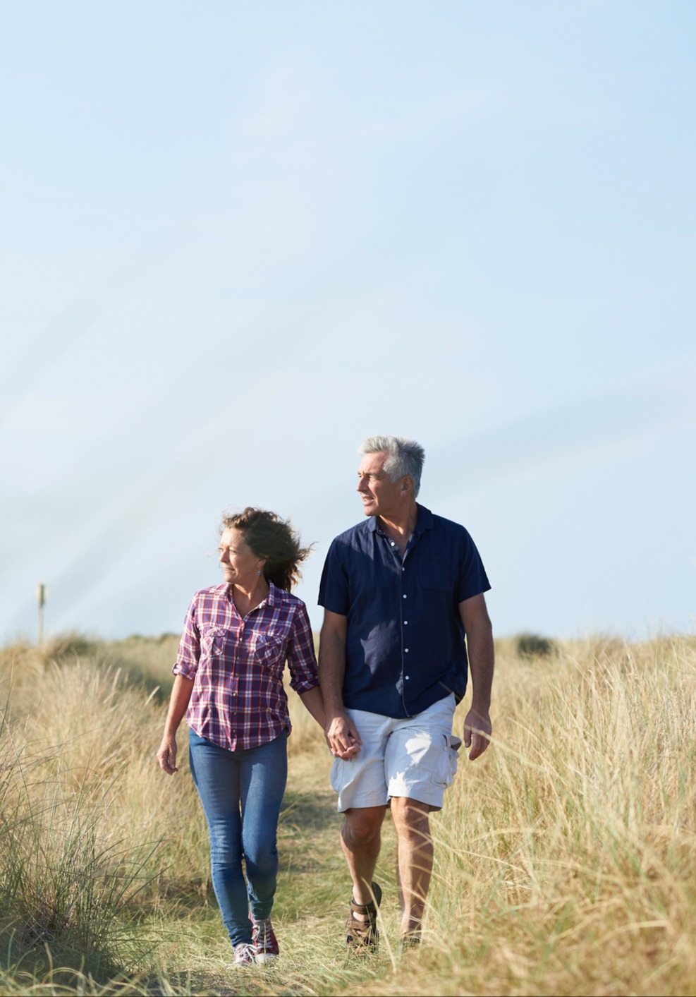 a couple walking next to tall grass