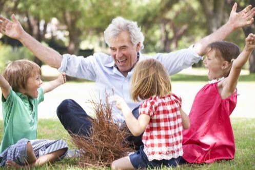 Grandfather teaching grandchildren to build a camp fire