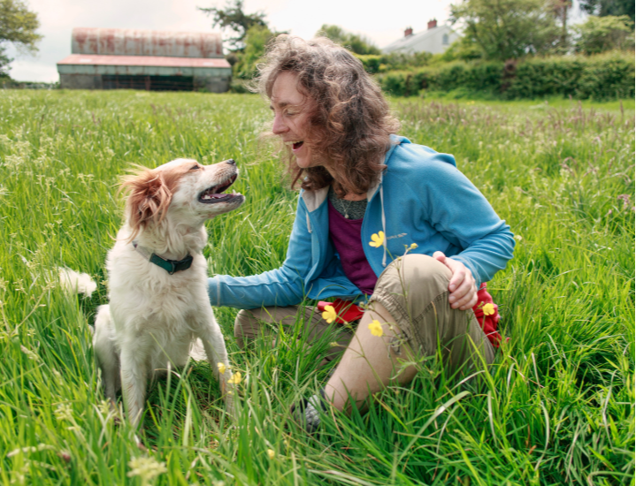 woman playing with a dog in a field