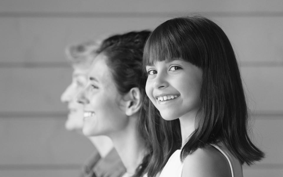 Little girl looking at camera while two other women are staring into the distance