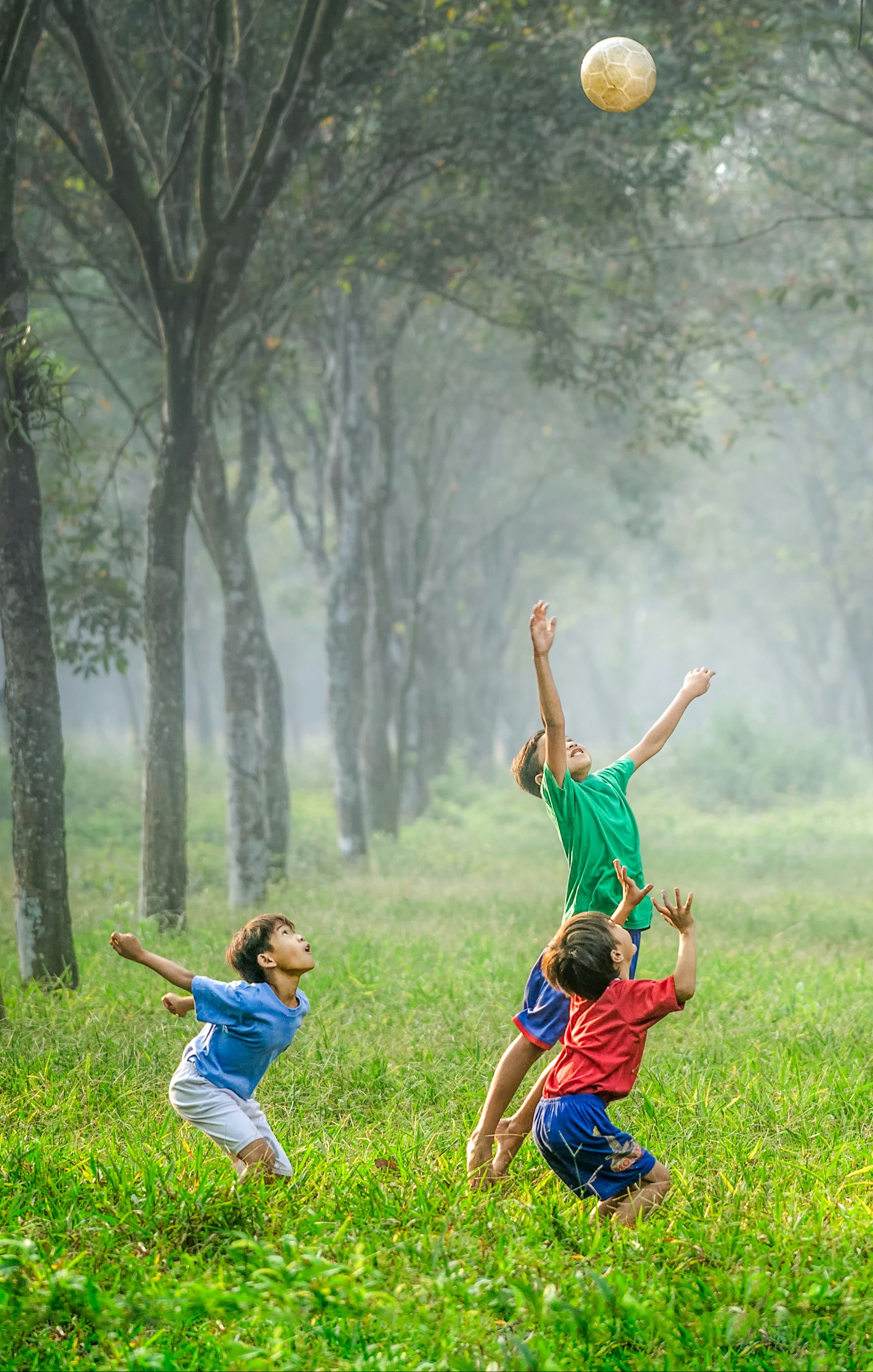 children outside jumping for to catch a ball