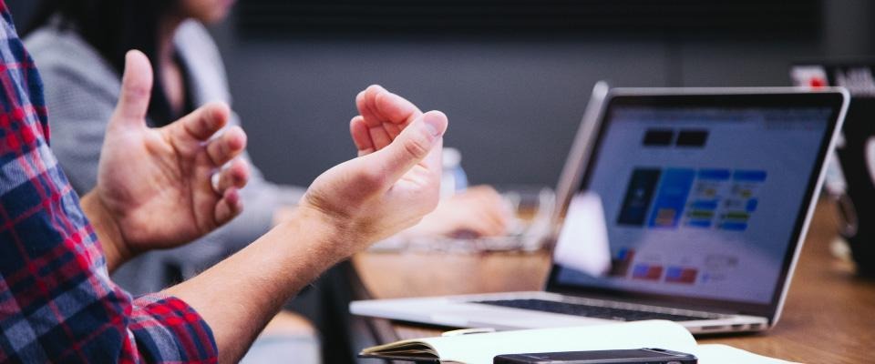 Photo of someone making hand gestures in front of a laptop