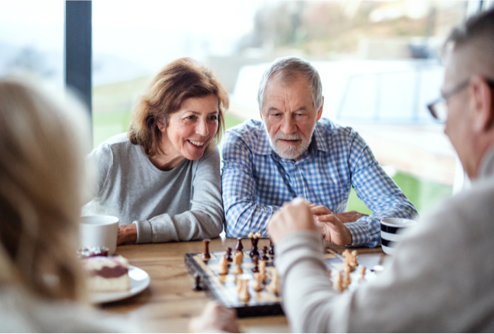 a couple drinking coffee and playing chess with friends
