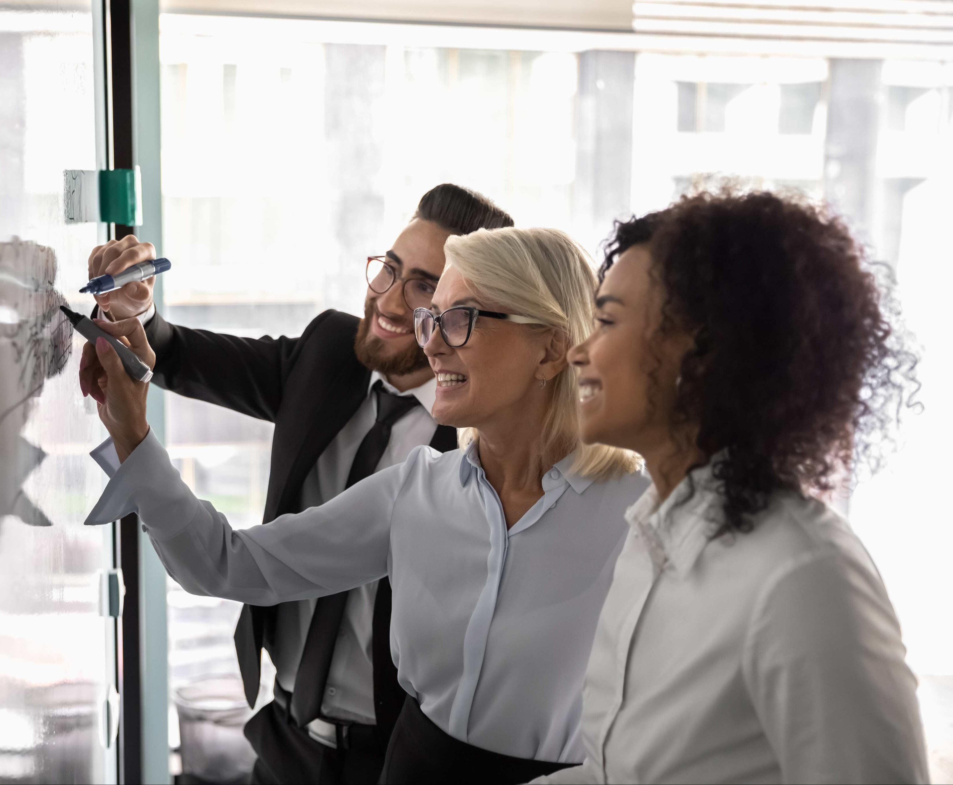 Three business people writing on a board