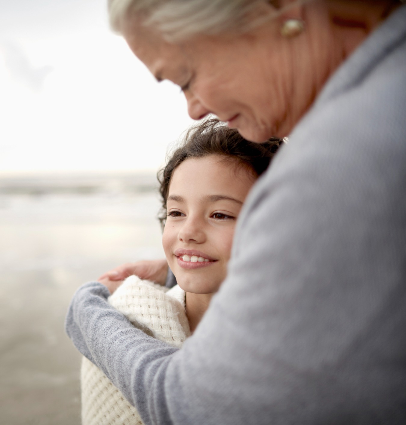 grandmother hugging grandchild on the beach