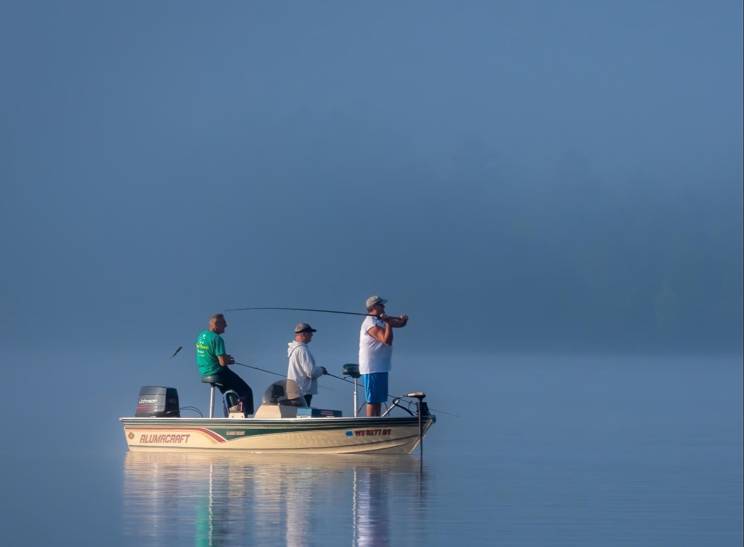 Photo of three men fishing on a small boat