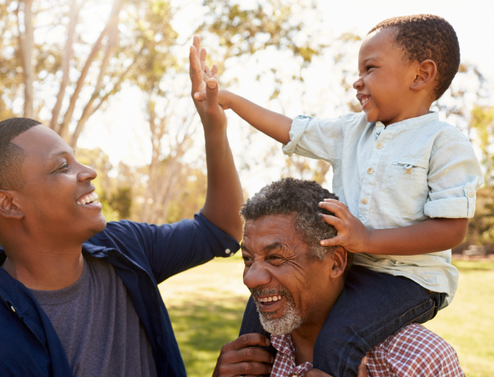 a grandfather, son and grandson having fun in a park
