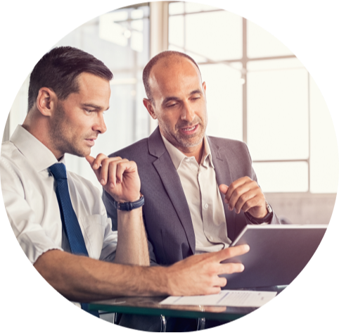 Two men speaking to each other in front of a tablet