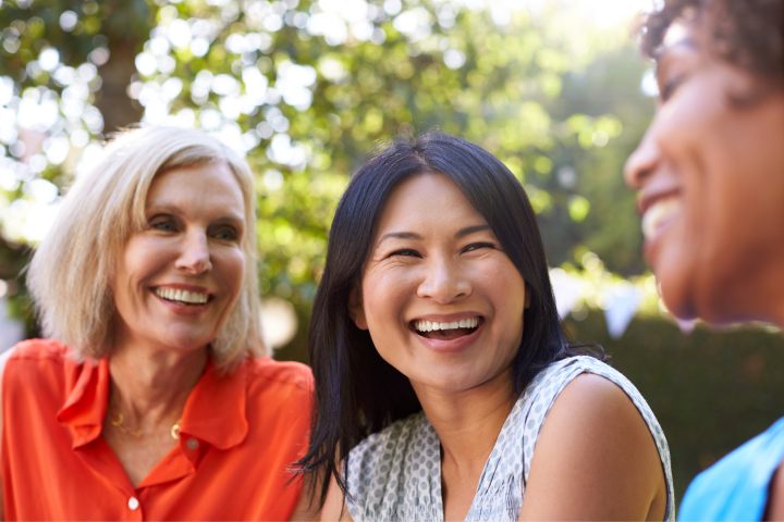 Three women sitting together, laughing.