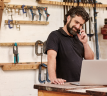 Man standing in the middle of a workspace on his phone.