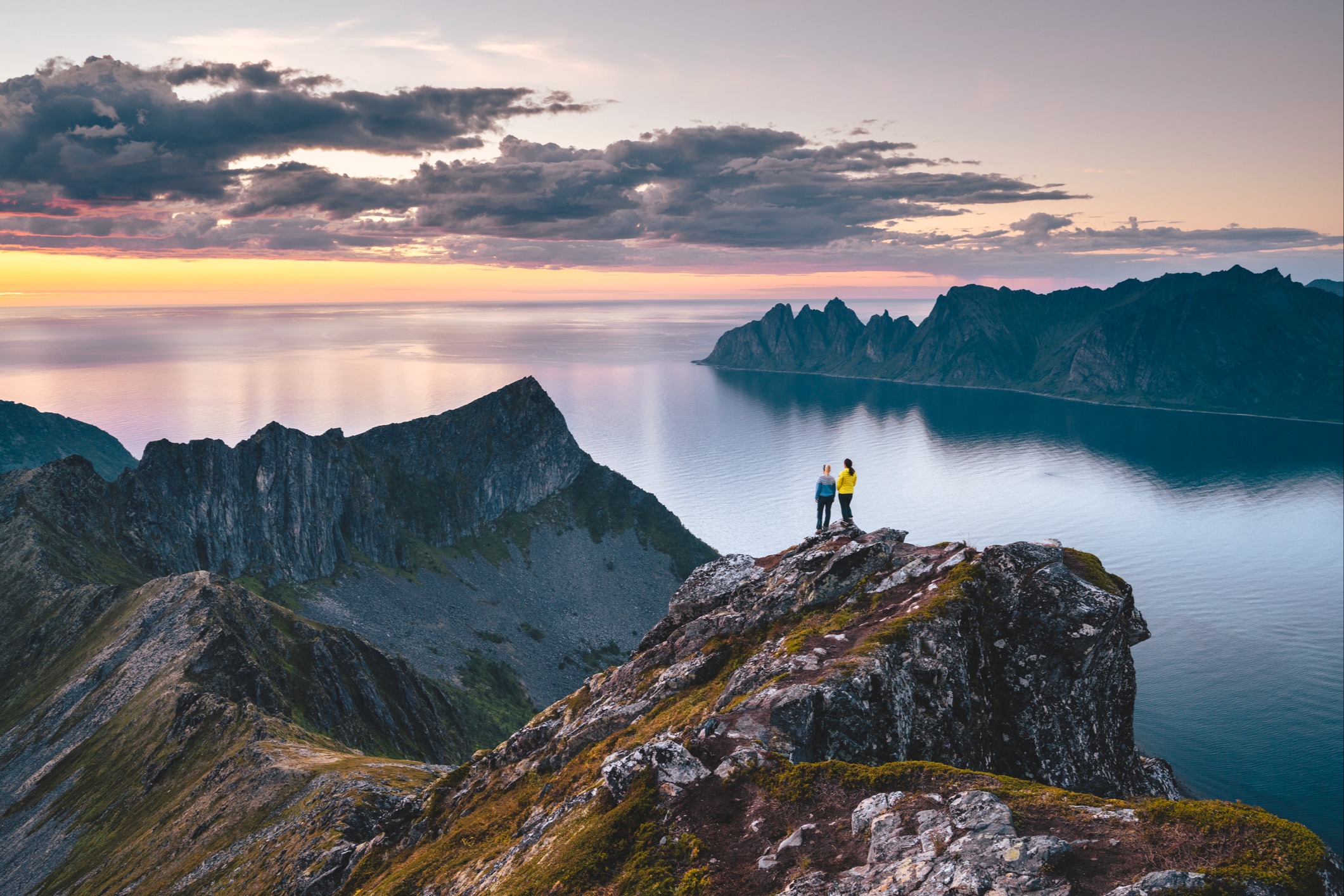 Two hikers on top of a mountain enjoying the view of ocean