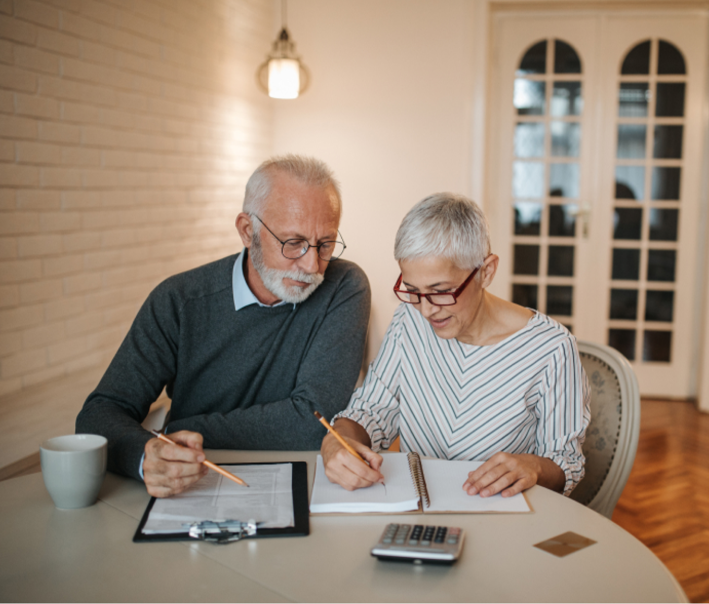 Man and woman holding pencils and taking notes at table