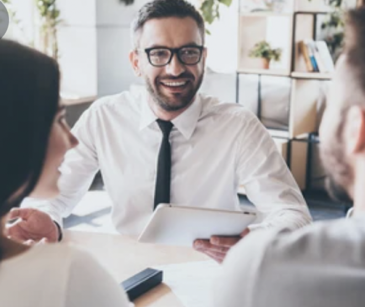 financial advisor smiling and meeting with two clients