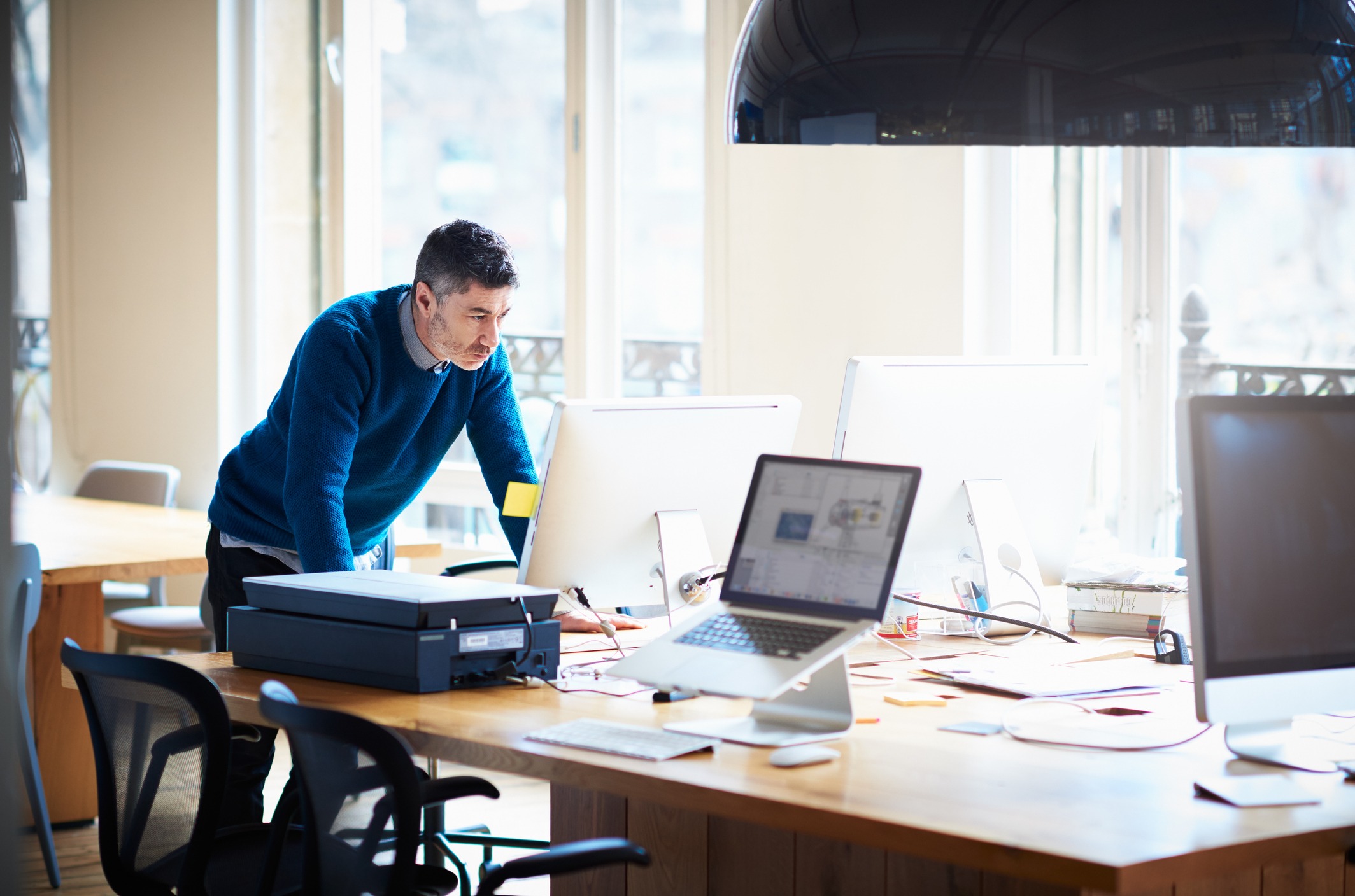 Man standing at desk looking at a computer