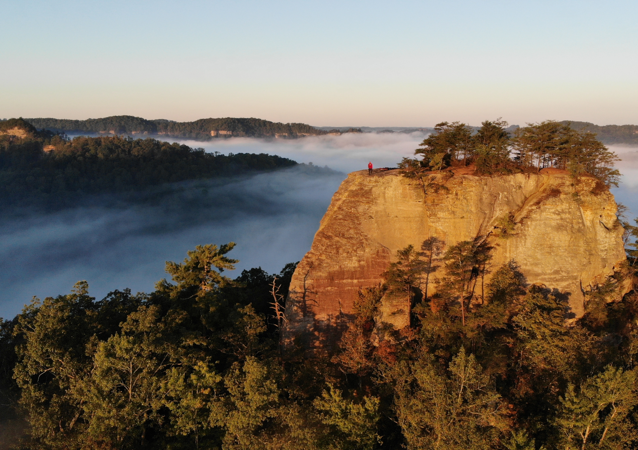 Photo of a man standing on a mountain in the distance