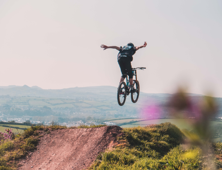 Mountain biker sending a no hander air off a dirt kicker ramp