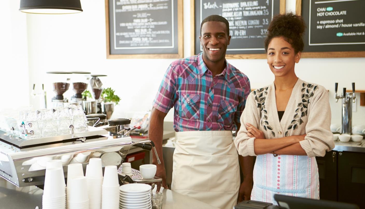 two people smiling working in a coffee shop together