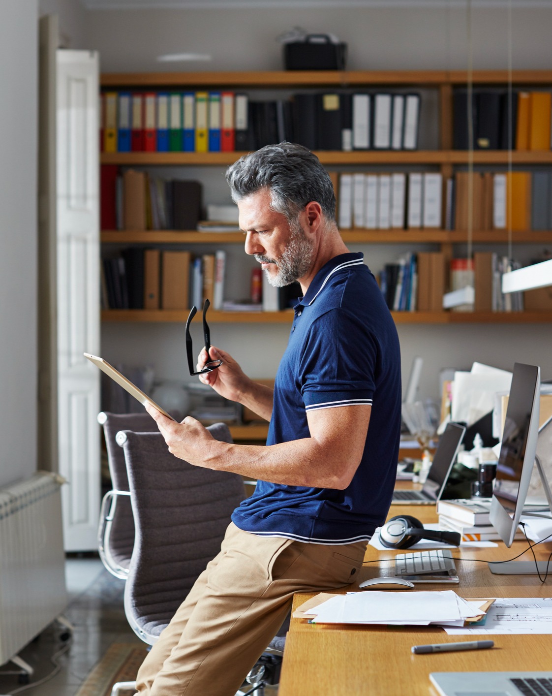 Man leaning against a desk and reading