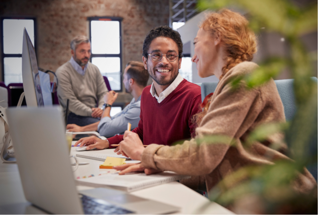 Two coworkers smiling during a conversation in office.